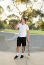 Young happy and attractive American man 30s standing holding skate board after sport boarding training session talking on mobile p