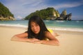 Young happy and attractive Asian Chinese woman in bikini excited at paradise beach sitting on sand by the sea enjoying idyllic