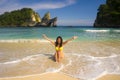 Young happy and attractive Asian Korean woman in bikini excited at paradise beach sitting on sand by the sea enjoying idyllic