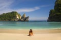 Young happy and attractive Asian Korean woman in bikini excited at paradise beach sitting on sand by the sea enjoying idyllic