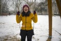 Young happy and attractive Asian Korean woman in Winter jacket and beanie enjoying snowfall at city park playing cheerful on swing Royalty Free Stock Photo