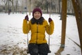 Young happy and attractive Asian Korean woman in Winter jacket and beanie enjoying snowfall at city park playing cheerful on swing Royalty Free Stock Photo