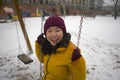 Young happy and attractive Asian Korean woman in Winter jacket and beanie enjoying snowfall at city park playing cheerful on swing Royalty Free Stock Photo