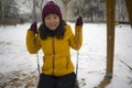 Young happy and attractive Asian Korean woman in Winter jacket and beanie enjoying snowfall at city park sitting on swing Royalty Free Stock Photo