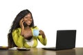 Young happy and attractive back afro American business woman drinking coffee relaxed working at home office desk talking on mobile Royalty Free Stock Photo