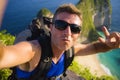Young happy and attractive backpacker man taking selfie portrait photo with mobile phone in front of amazing sea landscape smiling Royalty Free Stock Photo