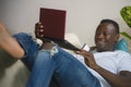 Young happy and attractive black African American man using credit card and laptop computer relaxed and cheerful at living room Royalty Free Stock Photo