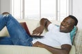 Young happy and attractive black African American man using credit card and laptop computer relaxed and cheerful at living room