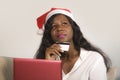 Young happy and attractive black African American woman in Santa Claus hat holding credit card buying Christmas present and gift o Royalty Free Stock Photo