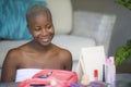 Young happy and attractive black african American woman wrapped in towel applying makeup cosmetics looking and smiling to herself Royalty Free Stock Photo