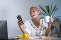 Young happy and attractive black afro american hipster woman working at home office with laptop computer using internet on mobile