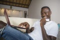 Young happy and attractive black afro American man using credit card and laptop computer relaxed and cheerful at living room sofa Royalty Free Stock Photo