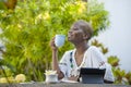 Young happy and attractive black afro American woman working with tablet outdoors at cafe relaxed drinking tea or coffee in digita Royalty Free Stock Photo