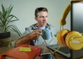 Young happy and attractive business man at home office drinking coffee cup looking satisfied and confident working with laptop com Royalty Free Stock Photo