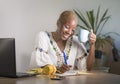 Young happy and attractive hipster black afro American woman drinking tea or coffee at home office working cheerful with laptop co Royalty Free Stock Photo