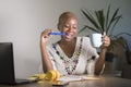 Young happy and attractive hipster black afro American woman drinking tea or coffee at home office working cheerful with laptop co Royalty Free Stock Photo