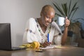 Young happy and attractive hipster black afro American woman drinking tea or coffee at home office working cheerful with laptop co Royalty Free Stock Photo