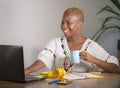 Young happy and attractive hipster black afro American woman drinking tea or coffee at home office working cheerful with laptop co Royalty Free Stock Photo