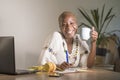 Young happy and attractive hipster black afro American woman drinking tea or coffee at home office working cheerful with laptop co Royalty Free Stock Photo