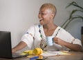 Young happy and attractive hipster black afro American woman drinking tea or coffee at home office working cheerful with laptop co Royalty Free Stock Photo