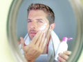 Young happy and attractive man applying moisturizer lotion or anti aging beauty cream smiling confident and conscious looking at b Royalty Free Stock Photo