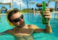 Young happy and attractive man listening to music with headset at tropical resort swimming pool drinking beer enjoying indulgent Royalty Free Stock Photo