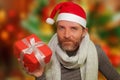 Young happy and attractive man in santa hat and scarf smiling holding Christmas gift box receiving or giving present isolated on Royalty Free Stock Photo
