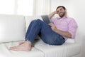 Young happy attractive man using digital pad or tablet sitting on couch Royalty Free Stock Photo