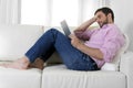 Young happy attractive man using digital pad or tablet sitting on couch Royalty Free Stock Photo