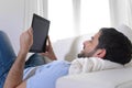 Young happy attractive man using digital pad or tablet sitting on couch Royalty Free Stock Photo