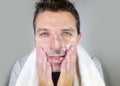 Young happy and attractive man washing face with anti aging soap lotion smiling confident and conscious looking at bathroom mirror Royalty Free Stock Photo