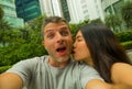 Young happy and attractive mixed Asian Caucasian ethnicity couple in love taking selfie picture together smiling and kissing enjoy