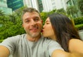 Young happy and attractive mixed Asian Caucasian ethnicity couple in love taking selfie picture together smiling and kissing enjoy