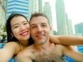 Young happy and attractive playful couple taking selfie picture together with mobile phone at luxury urban hotel infinity pool enj