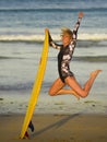 Young happy and attractive surfer girl jumping high in the air holding surf board before surfing at beautiful tropical beach enjoy Royalty Free Stock Photo