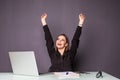 Young happy attractive woman at modern office desk, with laptop feeling with raised hands of celebreting cheerful good morning new