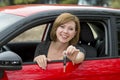 Attractive woman smiling proud sitting at driver seat holding and showing car key in new automobile buying and renting Royalty Free Stock Photo
