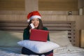 Young happy and beautiful Asian American girl on bed in Santa Christmas hat using credit card and laptop computer for online shopp Royalty Free Stock Photo