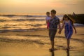 Young happy and beautiful Asian Chinese couple holding baby girl daughter walking on sunset beach enjoying together romantic Royalty Free Stock Photo