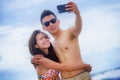 young happy and beautiful Asian Chinese couple taking selfie photo with mobile phone camera smiling joyful having fun on the beach Royalty Free Stock Photo