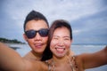 young happy and beautiful Asian Chinese couple taking selfie photo with mobile phone camera smiling joyful having fun on the beach Royalty Free Stock Photo