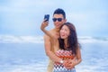 young happy and beautiful Asian Chinese couple taking selfie photo with mobile phone camera smiling joyful having fun on the beach Royalty Free Stock Photo