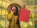 Young happy and beautiful Asian Chinese woman holding red shopping bag buying Christmas present in city mall smiling excited and Royalty Free Stock Photo