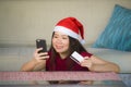 Young happy and beautiful Asian Chinese woman in Santa Claus hat holding credit card using mobile phone for Christmas online shopp Royalty Free Stock Photo