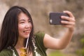 Young happy and beautiful Asian Chinese woman taking selfie photo with mobile phone posing playful and carefree in hipster Royalty Free Stock Photo