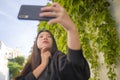 Young happy and beautiful Asian Japanese woman enjoying outdoors taking selfie with mobile phone at village garden playful and Royalty Free Stock Photo
