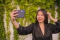 Young happy and beautiful Asian Japanese woman enjoying outdoors taking selfie with mobile phone at village garden playful and Royalty Free Stock Photo