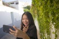 Young happy and beautiful Asian Japanese woman enjoying outdoors taking selfie with mobile phone at village garden playful and Royalty Free Stock Photo