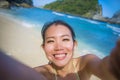 young happy and beautiful Asian Korean or Chinese tourist woman in bikini taking self portrait selfie photo at paradise beach Royalty Free Stock Photo