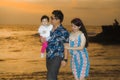 Young happy and beautiful Asian Korean couple holding baby girl daughter walking on sunset beach enjoying together romantic summer Royalty Free Stock Photo